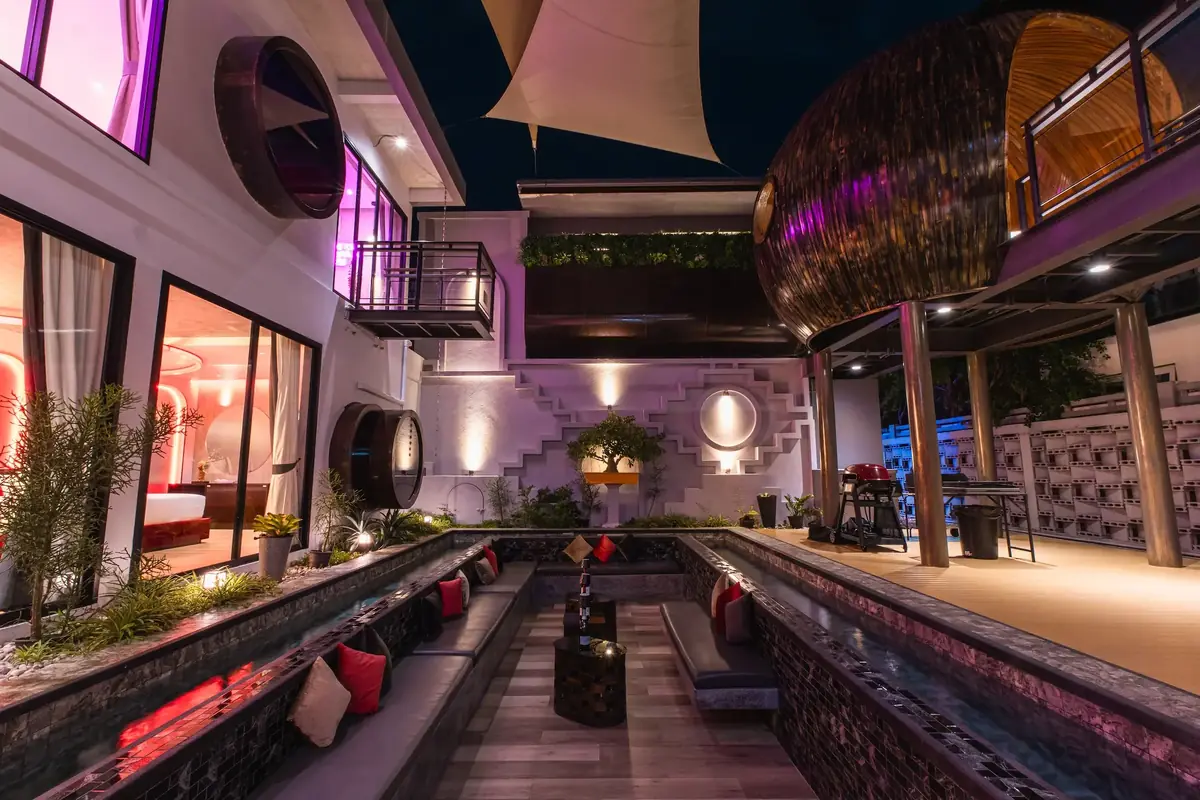 The villa courtyard at dusk, lit in pink and red